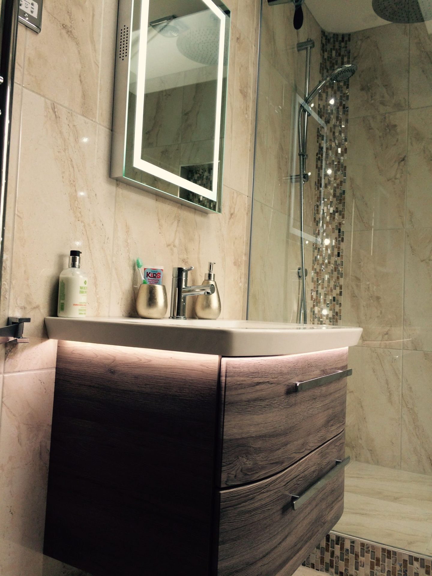 Fitted bathroom vanity with wood-effect drawers, LED mirror and marble-effect tiled walls