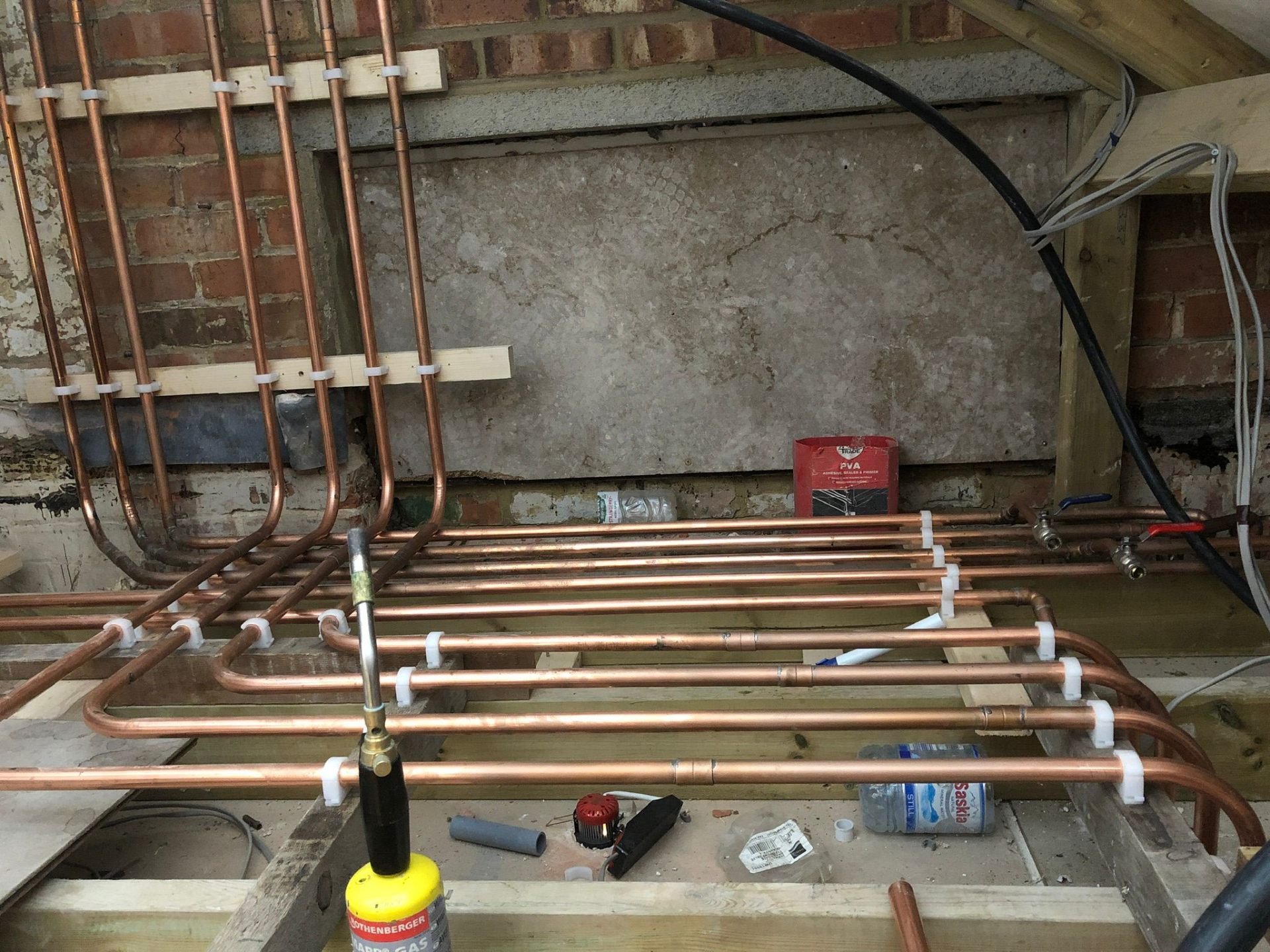Copper central heating pipework installed neatly across exposed floor joists
